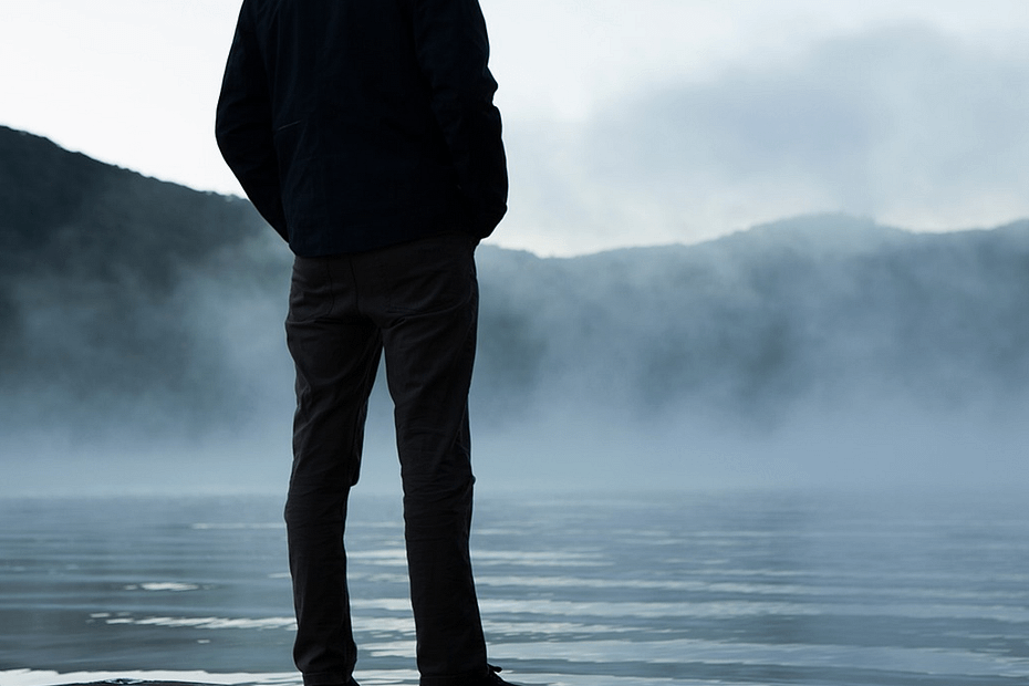 A man standing on a pier, looking out at the water